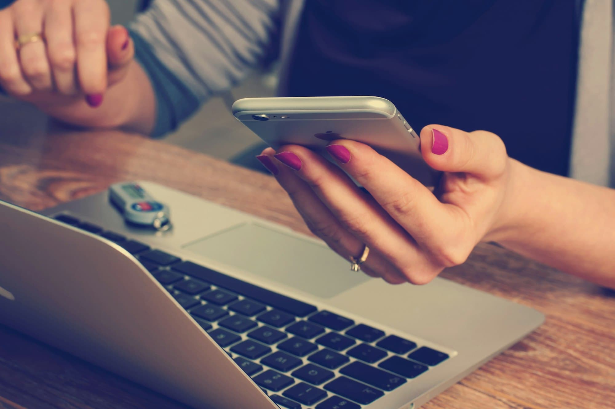 Iemand pakt de telefoon erbij naast een laptop